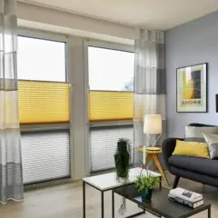 Modernes Wohnzimmer mit stilvoller Kombination aus gelben Wabenplissees und transparenten Gardinen.