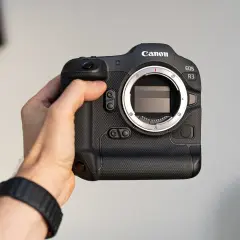 Dłoń trzyma aparat Canon EOS R3. Profesjonalny sprzęt gotowy do akcji.