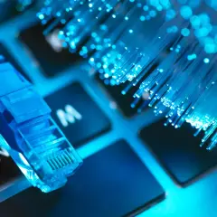 Niebieski kabel sieciowy i światłowody na klawiaturze symbolizują najlepszy internet.