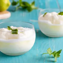 Due bicchieri di sorbetto al limone, guarniti con menta fresca, su un tavolo di legno blu.