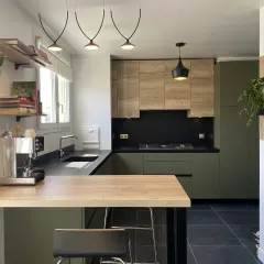 Cuisine moderne avec meubles verts et bois, plan de travail noir et îlot en bois.