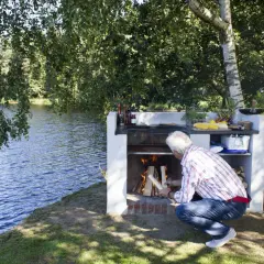 Man tänder en murad grill vid en sjö.