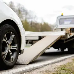 Białe auto na lawecie. Wygląda na to, że to szkoda całkowita w leasingu, auto jest zabierane przez pomoc drogową.