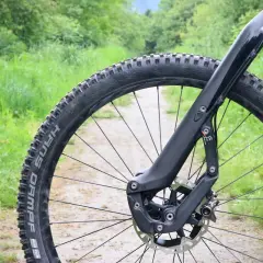 Close-up of a mountain bike's front wheel and fork on a dirt path, ready for adventure. This setup inspires trust and performance on any trail.