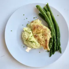 Na talerzu kurczak z puree ziemniaczanym, które jest źródłem węglowodanów, i zielone szparagi.
