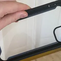 Dłoń trzyma czarne etui na telefon z przezroczystym tyłem. Dowiedz się, jak wyczyścić etui na telefon, aby wyglądało jak nowe.