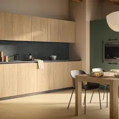 Un elegante montaggio cucina con ante in legno chiaro, piano scuro e un'isola centrale. La luce naturale illumina l'ambiente.