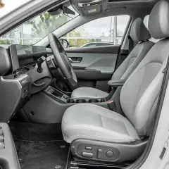 Wnętrze Hyundai Kona Hybrid z jasnoszarymi skórzanymi fotelami, nowoczesnym panelem sterowania i dużym ekranem multimedialnym.