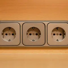Trzy gniazdka elektryczne na drewnianym tle. Nagle nastąpiło odłączenie prądu bez powiadomienia, pozostawiając je bezużytecznymi.