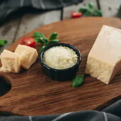 Kawałek parmezanu i starty ser w miseczce, idealne składniki, by dowiedzieć się, jaki ser do carbonary wybrać.