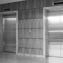 Dos ascensores modernos con puertas de acero inoxidable. Los ascensores tienen cámaras de seguridad integradas en el panel superior.