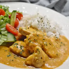 En krämig kyckling korma med ris och en fräsch sallad på tomat och gurka.
