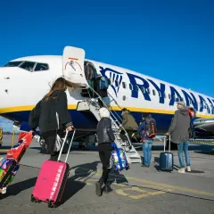 Odprawa Ryanair: pasażerowie z walizkami wchodzą po schodkach do samolotu.