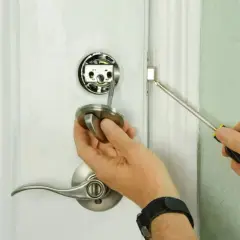 Main tenant démonte une poignée de porte pour savoir comment ouvrir une porte de chambre bloquée.