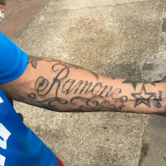 Damski tatuaż na przedramieniu z napisem "Ramone" i gwiazdką.