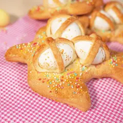 Scarcelle pugliesi ricetta originale: dolci a forma di colomba con uova sode, decorati con zuccherini colorati su tovaglia a quadretti rosa.