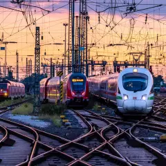 Mehrere Züge auf Bahngleisen bei Sonnenuntergang. Das Deutschlandticket gilt einen Monat lang.
