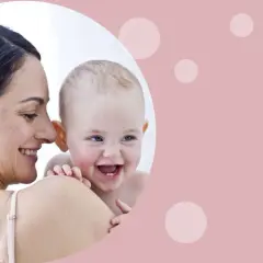 Uśmiechnięta mama tuli radosnego niemowlaka. Od kiedy oliwki dla niemowlaka? Pielęgnacja delikatnej skóry maluszka.
