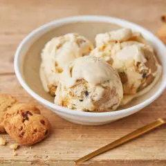 Schüssel mit cremigem Cookie Dough Eis, daneben Kekse und Löffel. Perfekt, um Cookie Dough Eis selber machen zu lernen.