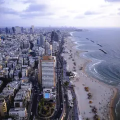 Widok z lotu ptaka na tętniące życiem miasto Tel Awiw, z jego nowoczesnymi wieżowcami i piaszczystą plażą nad Morzem Śródziemnym.