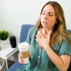 Donna con tachicardia, cerca di calmarla con un respiro profondo, tenendo una tazza.