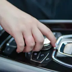 Main d'une personne actionnant un bouton sur la console centrale d'une voiture, peut-être pour savoir comment débloquer un frein à main automatique.