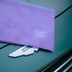 Fioletowa mikrofibra z logo Work Stuff na masce Aston Martina. Idealna do pielęgnacji auta.