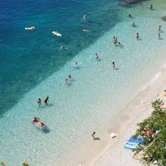 Słoneczne rijeka plaże z turkusową wodą. Ludzie pływają, opalają się i relaksują na kamienistym brzegu.