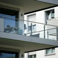 Nowoczesna loggia z przeszkloną balustradą, na której stoi stolik z krzesłami.