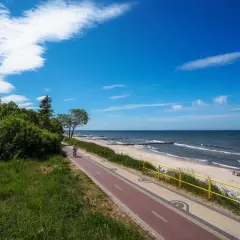 Ścieżka rowerowa nad Bałtykiem, plaża i morze w słoneczny dzień.
