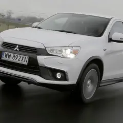 Biały Mitsubishi ASX 1.6 benzyna na mokrej drodze, z widocznym numerem rejestracyjnym WW 892XN.