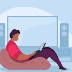 Person im Sessel mit Laptop, vor einem großen Bildschirm und Lautsprechern. Ein Beispiel für hybrides Arbeiten, flexibel und bequem.