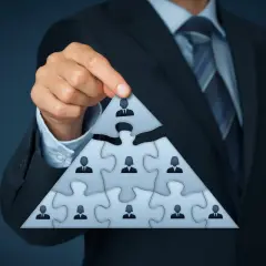 Biznesmen układa piramidę z puzzli, symbolizującą strukturę firmy i identyfikującą beneficjenta rzeczywistego.