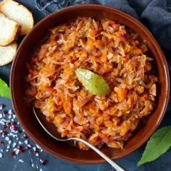 Miseczka bigosu z liściem laurowym, obok grzanki i przyprawy. Idealne jakie przyprawy do bigosu, by był pyszny!