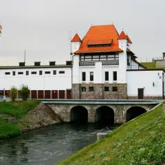 Elektrownia wodna Straszyn z charakterystycznym czerwonym dachem i kamienną podstawą, nad rwącą rzeką.