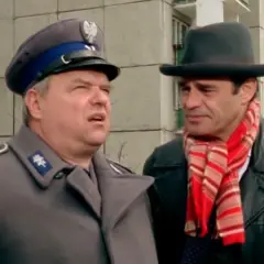 Dwóch mężczyzn, jeden w mundurze milicyjnym, drugi w kapeluszu i szaliku, w kadrze z kultowych bareja filmów.