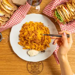 Tagliatelle al ragù, un classico italiano. Accanto, piadine farcite e un bicchiere di vino rosso.