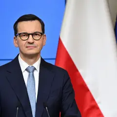 Mateusz Morawiecki w okularach, obok flagi Polski i UE. Jego rządzenie trwa od 2017 roku, kiedy to zastąpił Beatę Szydło.