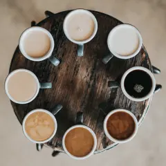 Åtta koppar kaffe i olika nyanser, från mörk espresso till ljus latte. En visuell guide till skillnad mellan latte och cappuccino.