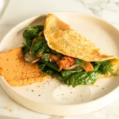 Omlet z air fryera z farszem ze szpinaku, grzybów i kimchi, podany z pomarańczowym hummusem.