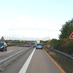 Achtung, stau schild warnt vor schleudernder Fahrbahn. Autos fahren auf der Autobahn.