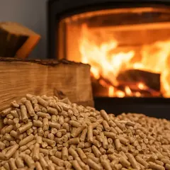 Stos drewna i pelletu przed palącym się piecem. Czy w piecu na węgiel można palić pelletem? To pytanie nurtuje wielu.