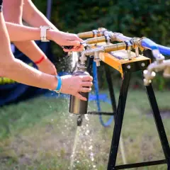 Manos llenando una botella de aluminio bajo un grifo.