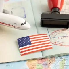 Flugzeugmodell, US-Flagge, Stempel und Pass auf einer Weltkarte. Perfekt für deine USA Reise Checkliste.