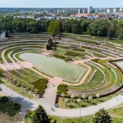 Widok z lotu ptaka na park cytadela z jeziorem, tarasami i alejkami. W tle widać miasto.
