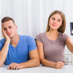 Znudzony chłopak obok dziewczyny robiącej selfie. Czy to objawy NPD?