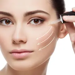 Kobieta aplikuje serum z kwasem hialuronowym, dbając o skórę w ciąży. Strzałki wskazują na liftingujące działanie.