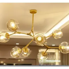 Elegante lámpara oro con esferas de cristal y luces cálidas, colgando del techo.