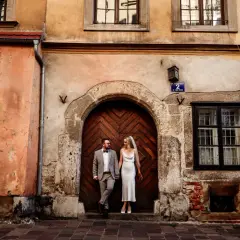 Para sesja w plenerze pomysły: para młoda stoi przed zabytkowymi drzwiami w kamienicy.