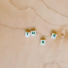 Litery "Ty" i "Я" na drewnianym tle. Zastanawiam się, jak ci minął dzień, co odpisać.